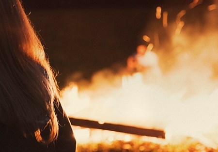 woman standing in front of blazing fire outside
